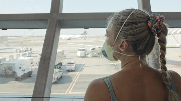 Mujer caucásica en el aeropuerto de Suvarnabhumi con máscara médica protectora en la cabeza contra el fondo del avión Concepto salud protección contra virus coronavirus epidemia sarscov2 covid19 2019ncov