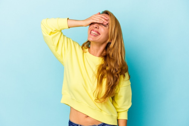 Mujer caucásica aislada sobre fondo azul se ríe con alegría manteniendo las manos en la cabeza. Concepto de felicidad.