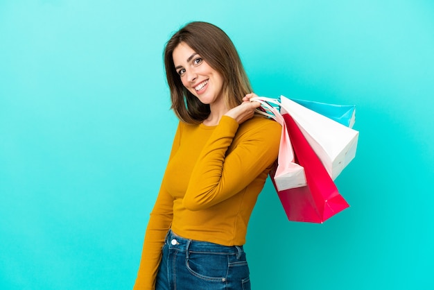 Mujer caucásica, aislado, en, pared azul, tenencia, bolsas de compras, y, sonriente