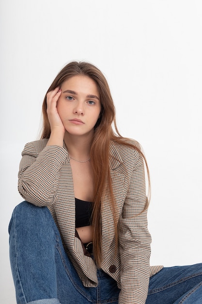 Mujer caucásica atractiva joven con el pelo largo y castaño en la chaqueta del traje en el estudio