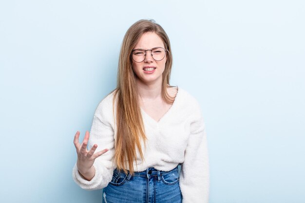 Mujer caucásica de cabello rojo que parece enojada, molesta y frustrada gritando wtf o qué te pasa