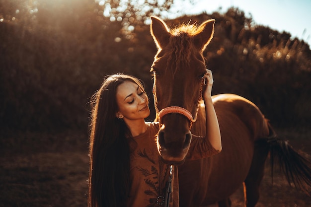 Mujer caucásica cerca de un caballo marrón durante un día soleado