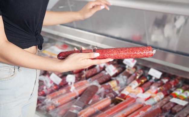 Mujer caucásica comprando salchichas en el supermercado.