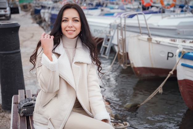 Una mujer caucásica despreocupada en ropa beige disfrutando de la vista del mar en un día cálido y ventoso