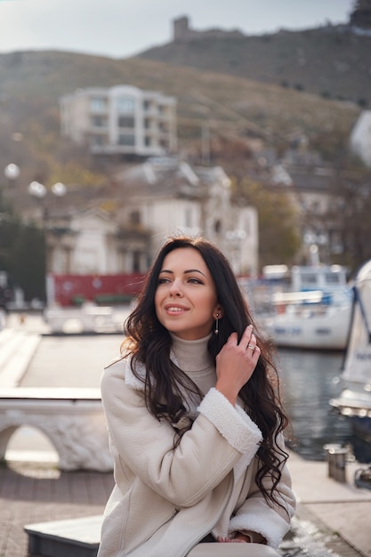 Una mujer caucásica despreocupada en ropa beige que disfruta de la vista del mar en un día caluroso y ventoso. dama disfrutando de un hermoso día de invierno y respirando el aire del mar