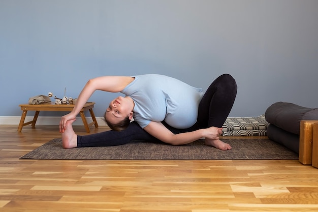 Mujer caucásica embarazada sentada en yoga asana