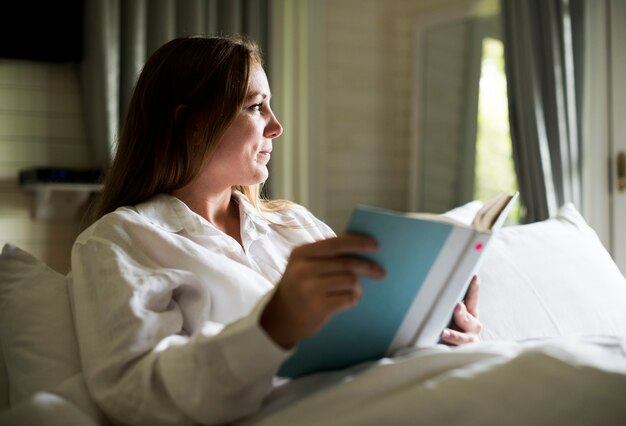 Una mujer caucásica está leyendo un libro.