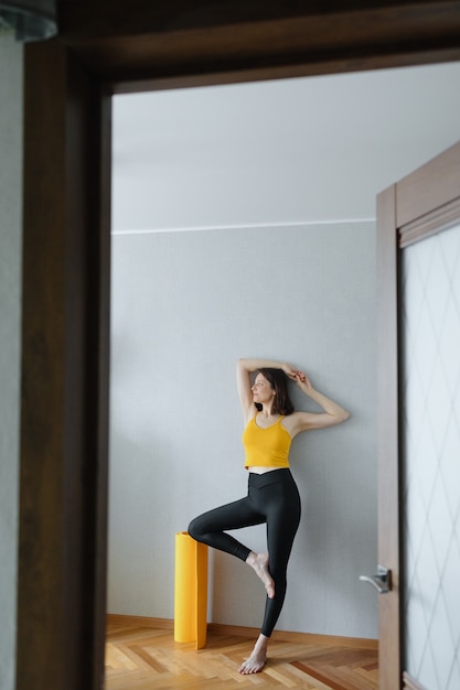 Foto mujer caucásica europea hace yoga y meditación en su casa casa calmante yoga en una alfombra amarilla