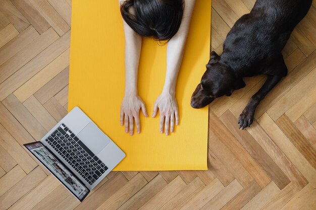 Mujer caucásica europea hace yoga y meditación en su casa casa calmante yoga en una alfombra amarilla