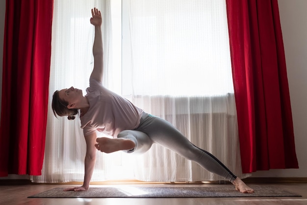 Foto mujer caucásica haciendo variación vasisthasana o pose de yoga side plank