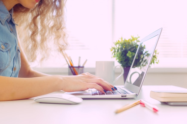 Mujer caucásica hermosa que se sienta y que trabaja en la computadora portátil