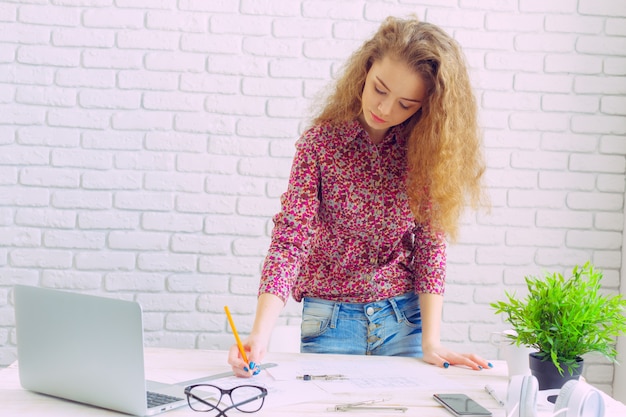 Mujer caucásica hermosa que se sienta y que trabaja en la computadora portátil