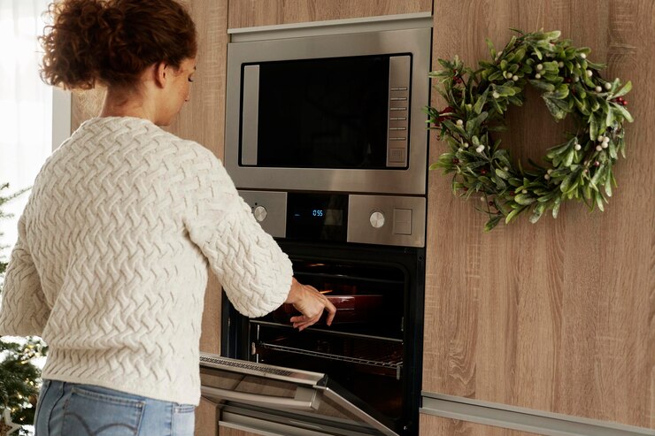 Foto mujer caucásica horneando galletas de pan de jengibre para navidad en el horno