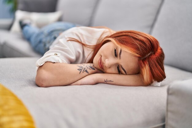Mujer caucásica joven acostada en el sofá durmiendo en casa