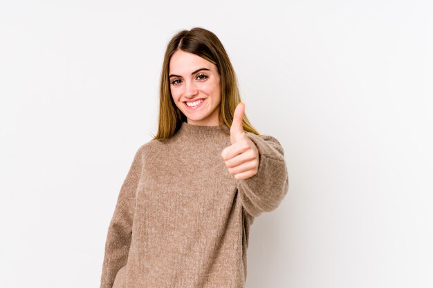 Mujer caucásica joven aislada en blanco que sonríe y que levanta el pulgar para arriba