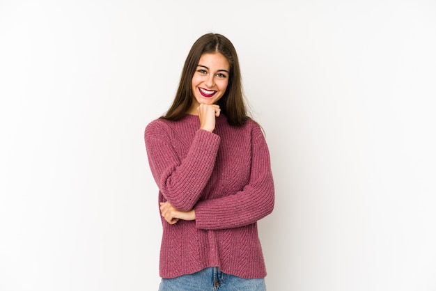 Mujer caucásica joven aislada en blanco sonriendo feliz y confiado, tocando la barbilla con la mano.