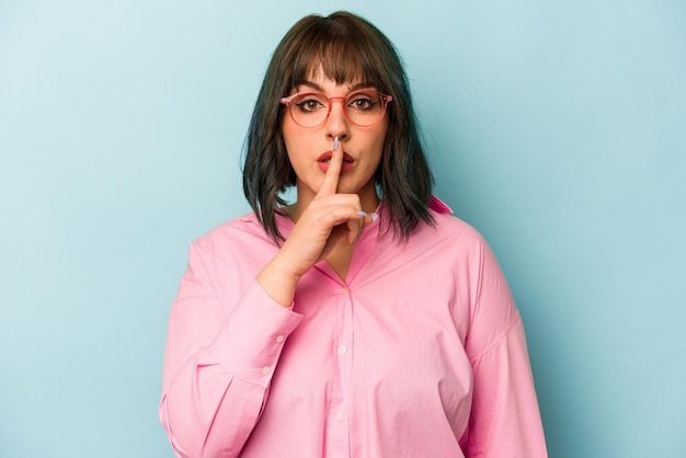 Mujer caucásica joven aislada de fondo azul guardando un secreto o pidiendo silencio