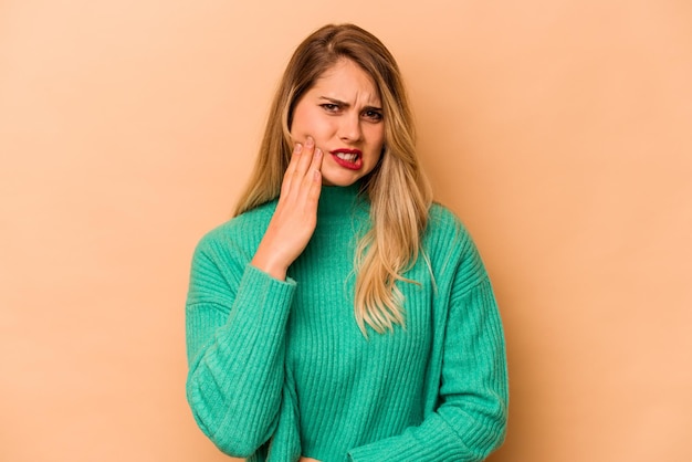 Mujer caucásica joven aislada de fondo beige que tiene un fuerte dolor de muelas