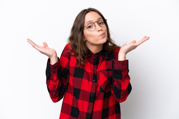 Foto mujer caucásica joven aislada de fondo blanco que tiene dudas mientras levanta las manos