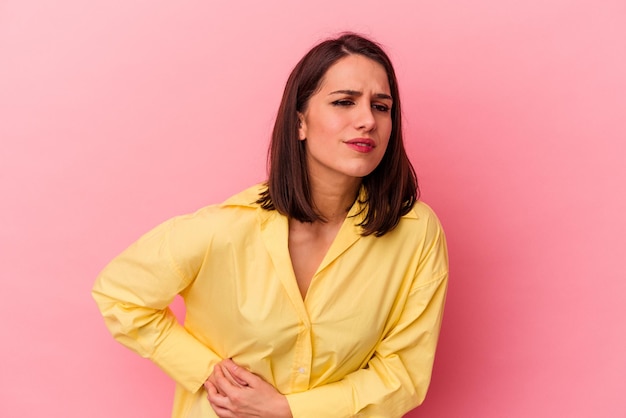 Mujer caucásica joven aislada de fondo rosa con dolor de estómago y dolor de hígado