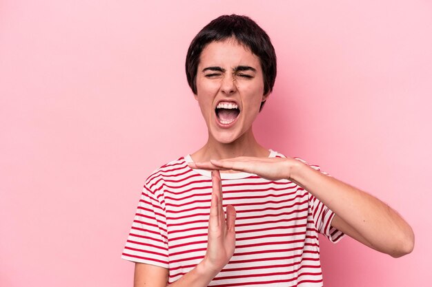 Mujer caucásica joven aislada de fondo rosa que muestra un gesto de tiempo de espera.