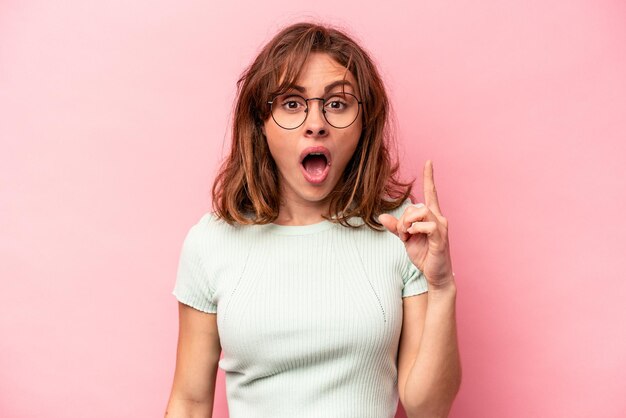 Mujer caucásica joven aislada en un fondo rosa que tiene una gran idea concepto de creatividad