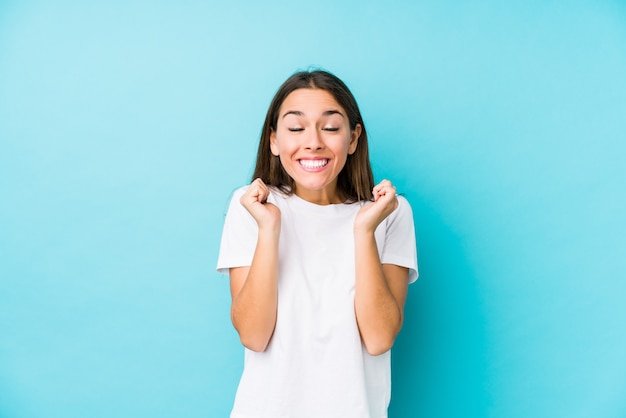 Mujer caucásica joven aislada levantando el puño, sintiéndose feliz y exitoso. Concepto de victoria