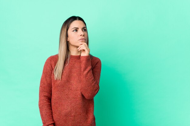 Mujer caucásica joven aislada mirando de lado con expresión dudosa y escéptica.