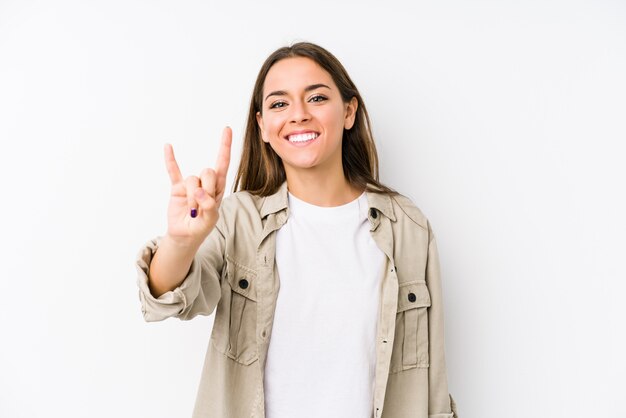 Mujer caucásica joven aislada mostrando un gesto de cuernos como un concepto de revolución.