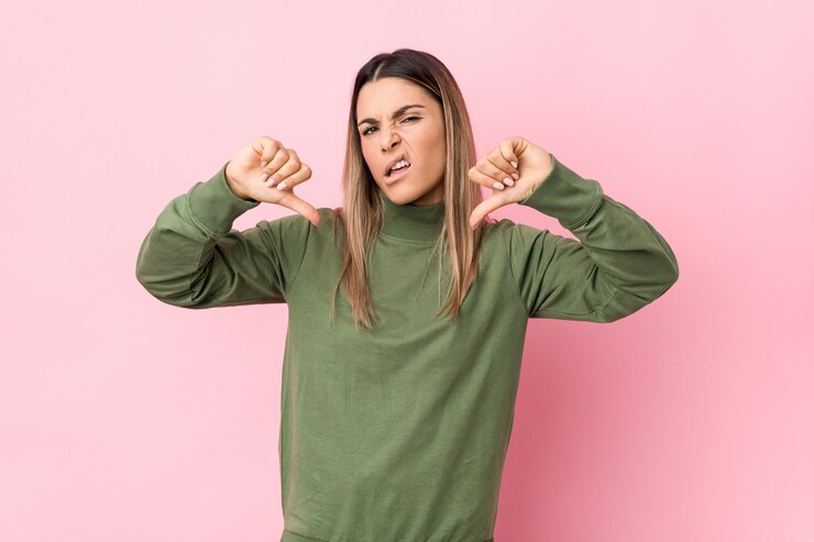 Foto mujer caucásica joven aislada mostrando el pulgar hacia abajo y expresando aversión.