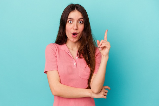 Mujer caucásica joven aislada en la pared azul que tiene una gran idea, concepto de creatividad.