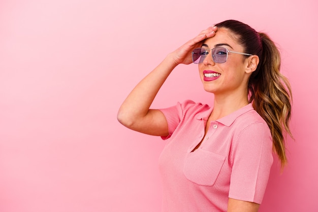 Mujer caucásica joven aislada en la pared rosada que ríe feliz, despreocupada, emoción natural.