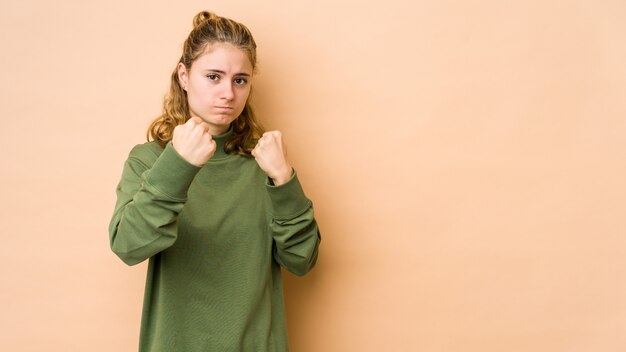 Mujer caucásica joven aislada en el puño que muestra beige, expresión facial agresiva.