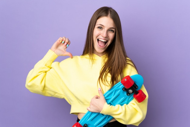 Mujer caucásica joven aislada en púrpura con un patín con expresión feliz