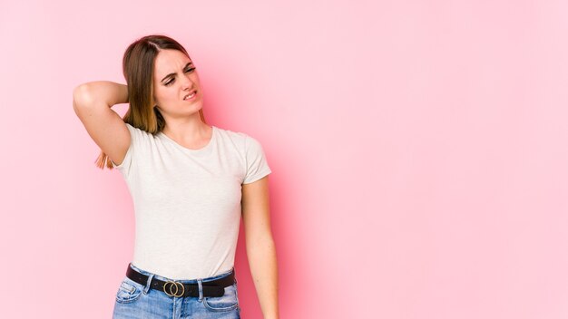 Mujer caucásica joven aislada en rosa cansada y con mucho sueño manteniendo la mano en la cabeza.