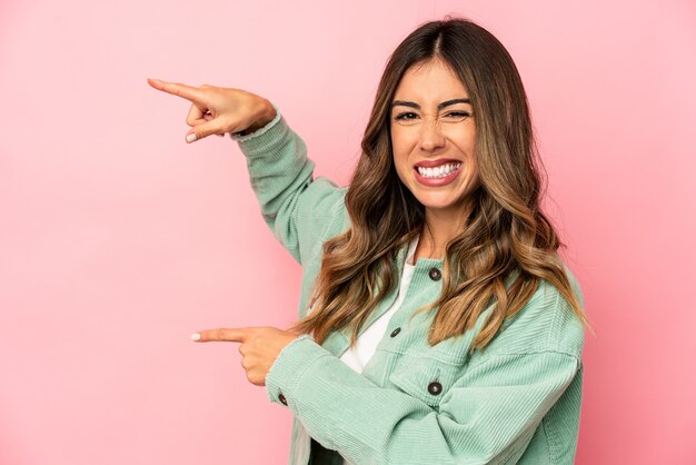 Mujer caucásica joven aislada señalando emocionado con los dedos índice lejos.