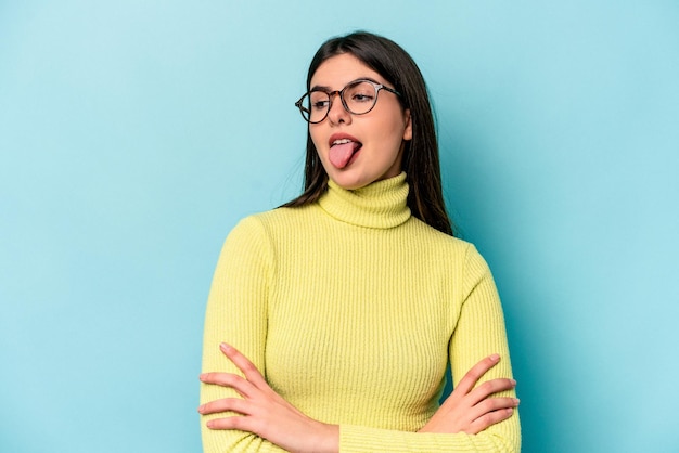 Mujer caucásica joven aislada sobre fondo azul divertida y amigable sacando la lengua