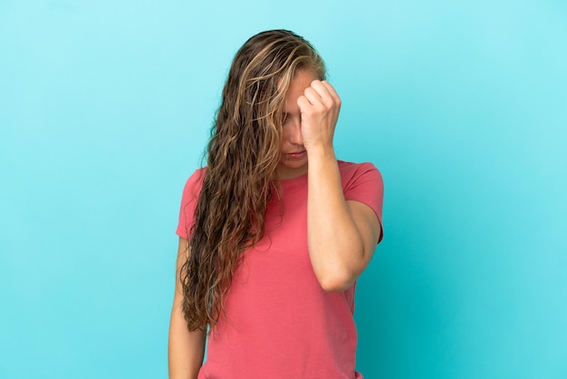 Mujer caucásica joven aislada sobre fondo azul con dolor de cabeza