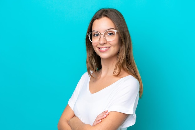 Mujer caucásica joven aislada sobre fondo azul con gafas con expresión feliz