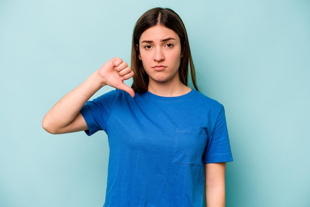 Mujer caucásica joven aislada sobre fondo azul que muestra un gesto de aversión pulgares hacia abajo Concepto de desacuerdo