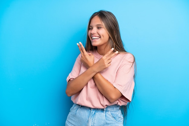 Mujer caucásica joven aislada sobre fondo azul sonriendo y mostrando el signo de la victoria