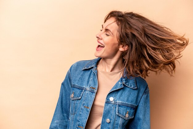 Mujer caucásica joven aislada sobre fondo beige bailando y divirtiéndose