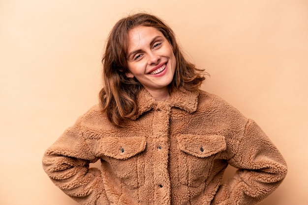 Mujer caucásica joven aislada sobre fondo beige feliz sonriente y alegre