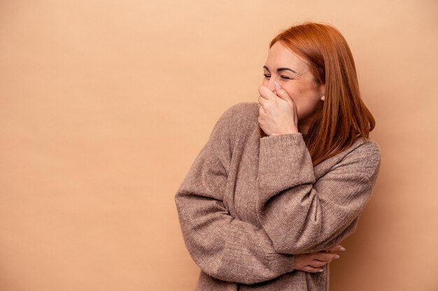 Mujer caucásica joven aislada sobre fondo beige riendo feliz emoción natural despreocupada