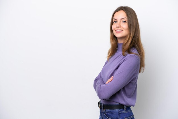 Mujer caucásica joven aislada sobre fondo blanco con los brazos cruzados y mirando hacia adelante