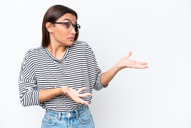 Mujer caucásica joven aislada sobre fondo blanco con expresión de sorpresa mientras mira hacia el lado