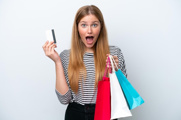 Mujer caucásica joven aislada sobre fondo blanco sosteniendo bolsas de compras y sorprendida