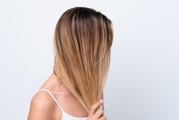 Foto mujer caucásica joven aislada sobre fondo blanco tocando su cabello retrato de cerca