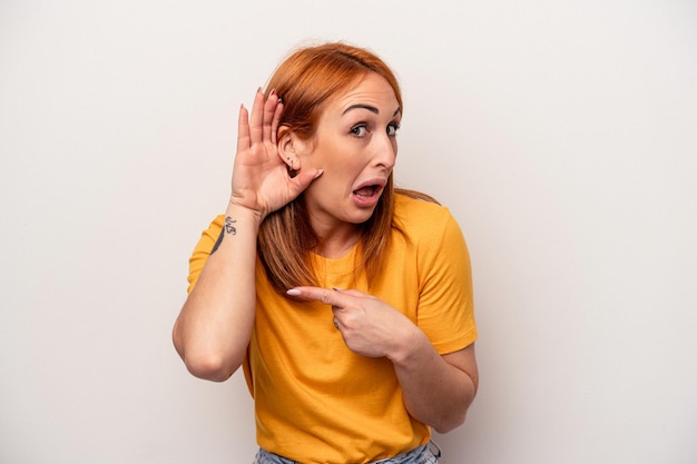 Mujer caucásica joven aislada sobre fondo blanco tratando de escuchar un chisme