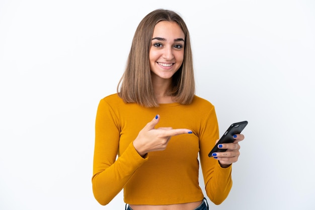 Mujer caucásica joven aislada sobre fondo blanco usando teléfono móvil y apuntándolo